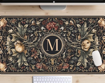 May include: A rectangular mouse pad with a floral design in shades of black, gold, and red. The center features a circular emblem with the letter "M". A white computer mouse and keyboard are visible.