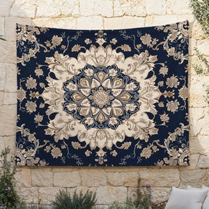 Puede incluir: Un tapiz rectangular con un fondo azul marino y un diseño central de medallón floral en beige, marrón claro y azul claro. El tapiz está colgado en una pared de piedra, creando un espacio decorativo al aire libre.