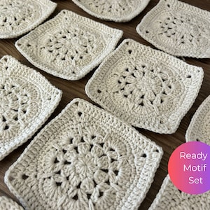 Puede incluir: Un conjunto de cuadrados de ganchillo de color crema con un patrón floral. Los cuadrados están dispuestos en un patrón escalonado sobre una superficie de madera. El texto "Ready Motif Set" es visible en la esquina inferior derecha de la imagen.