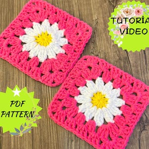 May include: Two pink and white crochet squares with a daisy flower design in the center. The squares are on a wooden surface. The text "PDF PATTERN" and "TUTORIAL VIDEO" are visible in the image.