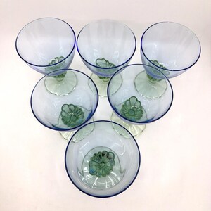 K&ouml;nnte beinhalten: Sechs transparente Weingl&auml;ser mit blauem Rand und gr&uuml;nem Blumendesign am Boden. Die Gl&auml;ser sind kreisf&ouml;rmig angeordnet und pr&auml;sentieren ihr elegantes Design. Ideal zum Servieren von Getr&auml;nken bei einer besonderen Veranstaltung.