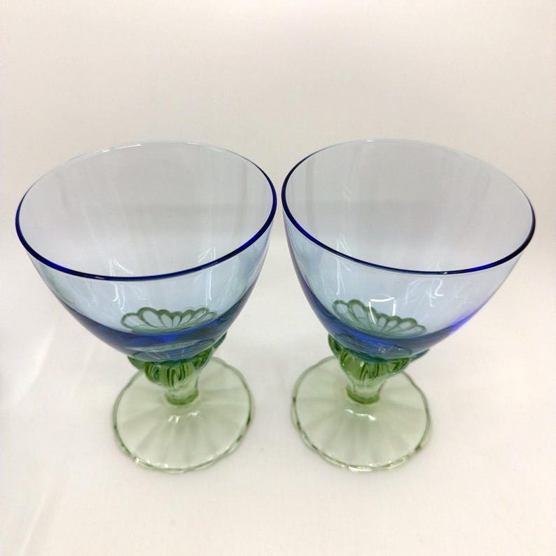 K&ouml;nnte beinhalten: Zwei transparente Weingl&auml;ser mit blauem Rand und hellblauem Kelch. Der Fu&szlig; ist gr&uuml;n mit einem floralen Design. Der Stiel ist gr&uuml;n und der Fu&szlig; hellgr&uuml;n.