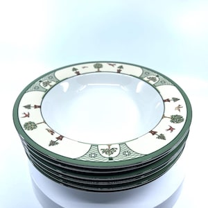 May include: A stack of white ceramic soup bowls with a green and cream-colored border. The border features a repeating pattern of trees, birds, and geometric shapes. The bowls have a deep, rounded shape.