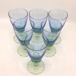 K&ouml;nnte beinhalten: Sechs Vintage-Stielgl&auml;ser in Blau und Gr&uuml;n, kreisf&ouml;rmig angeordnet. Die Gl&auml;ser haben eine hellblaue Schale, einen gr&uuml;nen Stiel und einen gewellten Fu&szlig;. Die Stiele haben ein dekoratives Blumenmuster.
