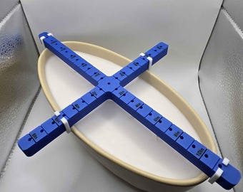 May include: A blue plastic candle centering tool with white clips. The tool has markings in inches from 1 to 10. The tool is placed inside a white oval ceramic bowl.