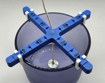 May include: Blue candle centering tool with white clips, marked in 1/2 inch increments, holding a wick centered in a clear glass jar.