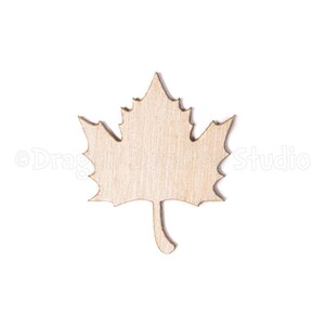 Puede incluir: Recorte de hoja de arce de madera, con un acabado de veta de madera natural. La hoja tiene un borde detallado y texturizado y un pequeño tallo. Ideal para manualidades o decoración otoñal.