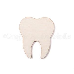 May include: A wooden tooth cutout, featuring a natural wood grain texture. The tooth has a rounded crown and two roots, ideal for dental-themed crafts or decor. The background is plain white.