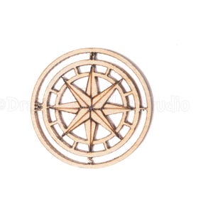 Puede incluir: Una rosa de los vientos de madera clara, con un diseño de estrella dentro de un marco circular. La rosa de los vientos es de color marrón claro y parece estar cortada con láser. El diseño está centrado sobre un fondo blanco.