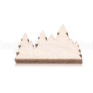 Pode incluir: Um recorte de madeira de uma cordilheira. A peça de madeira natural apresenta uma série de picos estilizados e uma base plana. O design é simples e adequado para artesanato ou fins decorativos. O recorte tem aproximadamente 10 cm de largura.