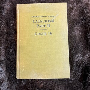 May include: A yellow book with the title "GRADED LESSONS' SYSTEM CATECHISM PART II GRADE IV" printed on the cover.