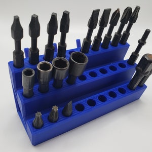 May include: A blue plastic organizer with 20 slots for holding screwdriver bits and socket attachments. The organizer is filled with various bits and attachments, including Phillips head, flat head, and hex bits.