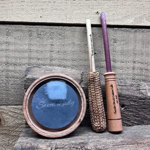 May include: A white ceramic mug with a black handle and the text "But First, Coffee" in a black, handwritten-style font. The mug is on a white surface.