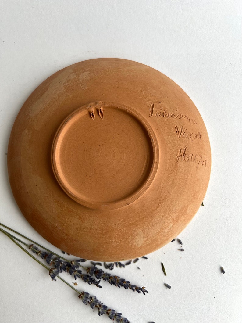 May include: A terracotta plate with a hand-written inscription on the bottom that reads "Tauerner Volkskunst".