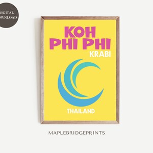 May include: A yellow poster with the text "KOH PHI PHI KRABI THAILAND" in pink and blue lettering. A blue wave graphic is in the centre of the poster.