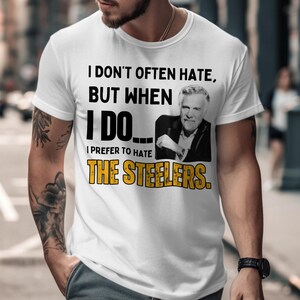 May include: White t-shirt with the text "I DON'T OFTEN HATE, BUT WHEN I DO... I PREFER TO HATE THE STEELERS." The shirt features a black and white image of a man. The text "THE STEELERS" is in yellow.