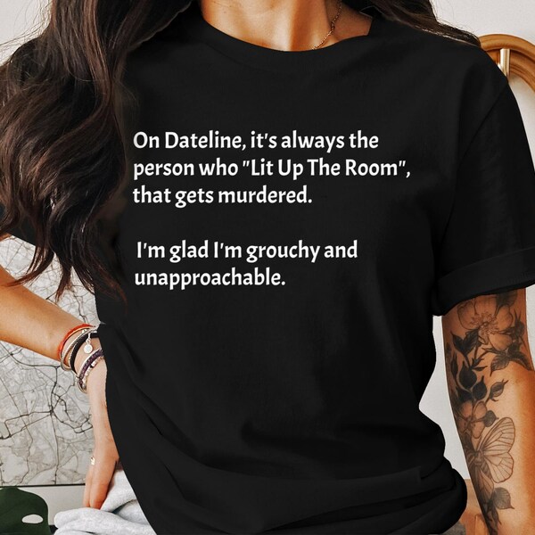 May include: Black t-shirt with white text that reads "On Dateline, it's always the person who "Lit Up The Room", that gets murdered. I'm glad I'm grouchy and unapproachable."