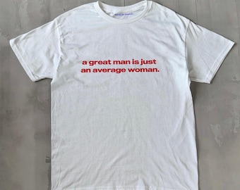 Könnte beinhalten: Weißes T-Shirt mit dem roten Text "a great man is just an average woman." Das Shirt hat einen Rundhalsausschnitt und kurze Ärmel. Der Text ist mittig auf der Vorderseite des Shirts platziert.