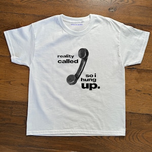 May include: White t-shirt with a black and white graphic of a rotary phone with the text "reality called so i hung up."