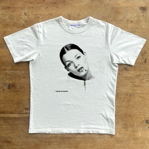 May include: White t-shirt featuring a black and white image of a woman's face with a cigarette in her mouth. The text "when in doubt." is printed below the image.