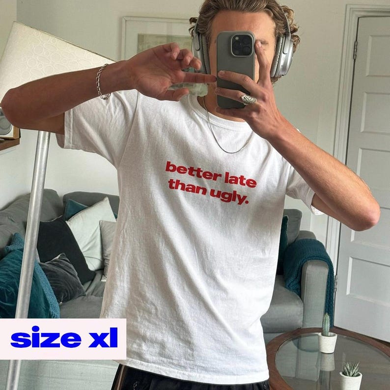 May include: White XL t-shirt with the text "better late than ugly" in red. The shirt is short-sleeved and has a crew neck. The image shows the shirt being worn.