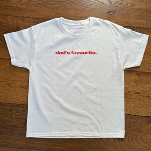May include: White t-shirt with the text "dad's favourite." printed in red on the front.