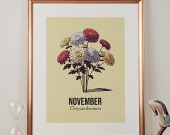 May include: A framed print with a yellow background featuring a bouquet of chrysanthemums in shades of red, white, and yellow. The text "NOVEMBER" and "Chrysanthemum" is printed below the flowers.