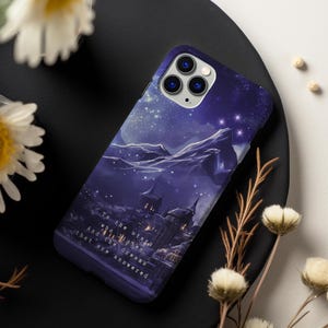 May include: A purple and blue phone case featuring a starry night sky with a castle in the distance. The text on the case reads "To the stars who listen and the dreams that are answered."