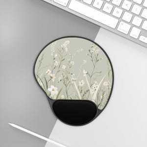 May include: Ergonomic mouse pad with a black wrist rest and a floral design. The pad features a light green background with white flowers and green stems. The mouse pad is designed to provide comfort and support during computer use.