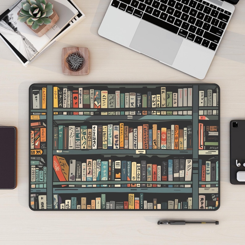 May include: A black and white illustration of a bookshelf filled with colourful books. The books have Japanese text on their spines. The bookshelf is on a light wood surface.