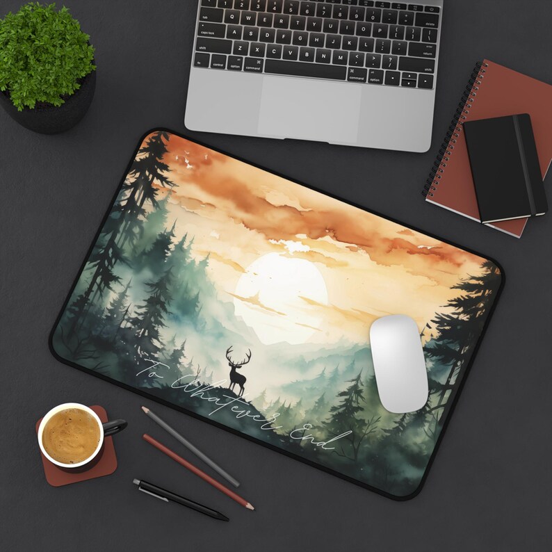 Pu&ograve; includere: Un tappetino per mouse ad acquerello con una scena di foresta e una silhouette di cervo. Lo sfondo &egrave; un tramonto con un grande sole bianco. Il testo "To Whatever End" &egrave; scritto in bianco con calligrafia in fondo al tappetino per mouse.