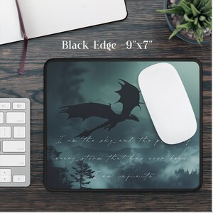 May include: A black mouse pad with a dark green and blue background featuring a silhouette of a dragon flying through the clouds. The text "I am the sky and the proof of every storm that has ever been. I am infinite." is printed on the mouse pad.