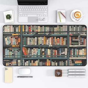 May include: A black and white desk mat with a bookshelf design featuring rows of colourful books with Japanese text. The bookshelves are on a dark blue background.
