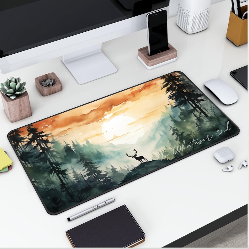Pu&ograve; includere: Un tappetino per mouse in stile acquerello con una scena di tramonto su una foresta. Un cervo si trova in primo piano, e il testo "To whatever end" &egrave; scritto in bianco.