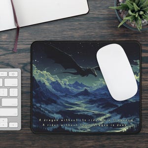 May include: A black mousepad with a dark blue and green landscape scene featuring a black dragon flying over mountains. The text "A dragon without its rider is a tragedy. A rider without their dragon is dead." is printed at the bottom of the mousepad.