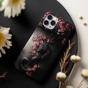 May include: Black phone case with a black dragon and pink cherry blossoms. The phone case has a camera lens cutout with three black circles.