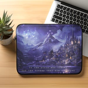 May include: A laptop sleeve featuring a fantasy landscape with a castle, mountains, and a starry sky in shades of purple and blue. The text reads, "To the stars who listen, And the dreams that are answered."