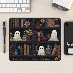Puede incluir: Una ilustraci&oacute;n en blanco y negro de una estanter&iacute;a con fondo oscuro. La estanter&iacute;a est&aacute; llena de libros y tiene tres fantasmas blancos en los estantes. Los fantasmas flotan frente a los libros.