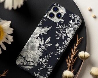 Peut inclure: Une coque de téléphone noire avec un motif floral blanc. La coque a une découpe pour l'objectif de l'appareil photo et un fond noir.