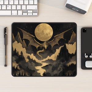 Puede incluir: Una alfombrilla de ratón negra y dorada con un dragón volando frente a una luna llena. El dragón es dorado y la luna es blanca. El fondo es azul oscuro con estrellas.