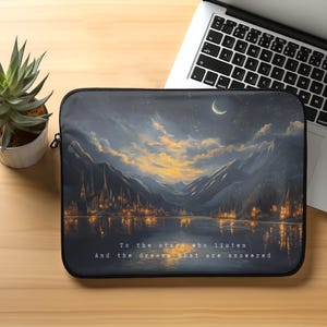 May include: A laptop sleeve with a dark blue background featuring a nighttime scene of a lake with a town in the distance, mountains in the background, and a crescent moon in the sky. The text "To the stars who listen And the dreams that are answered" is printed in white at the bottom of the sleeve.