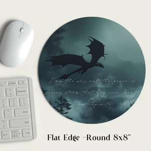 May include: A round mousepad with a dark green and blue background featuring a silhouette of a dragon flying over a mountain range. The text "I am the sky and the power of every storm that has ever been. I am infinite." is printed on the mousepad. The mousepad is 8 inches in diameter.