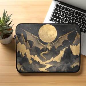 May include: A black laptop sleeve featuring a gold dragon flying in front of a full moon and mountains. The dragon is surrounded by clouds and stars.