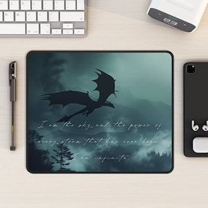 May include: A dark blue mousepad with a silhouette of a dragon flying over a misty forest. The text "I am the sky and the power of every storm that has ever been. I am infinite." is printed on the mousepad.