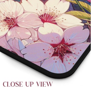 May include: Close-up of a pink and white floral print mousepad with a black stitched edge. The flowers are stylized and have a soft, watercolor-like appearance.