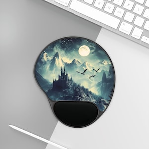 Puede incluir: Alfombrilla de ratón ergonómica con reposamuñecas. La almohadilla presenta un diseño de paisaje de fantasía con un castillo, montañas, luna llena y pájaros volando. La paleta de colores incluye tonos de azul, gris y negro.