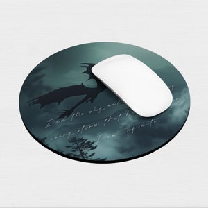 May include: A round mouse pad with a dark green and black design featuring a silhouette of a dragon flying through a stormy sky. The text "I am the sky and every storm that breaks I am infinite." is printed on the mouse pad.