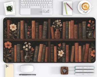 May include: A black desk mat featuring a bookshelf design with rows of vintage books in shades of brown and tan. The mat includes floral accents and is surrounded by office supplies, including a laptop, phone, and coffee cup.