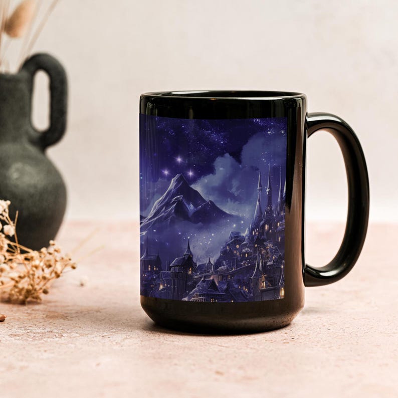 K&ouml;nnte beinhalten: Schwarze Keramiktasse mit einem Fantasy-Landschaftsdesign. Das Kunstwerk zeigt eine Bergkette, ein Schloss und einen Sternenhimmel in Blau- und Lilat&ouml;nen. Die Tasse hat einen gro&szlig;en Henkel und ein gl&auml;nzendes Finish.