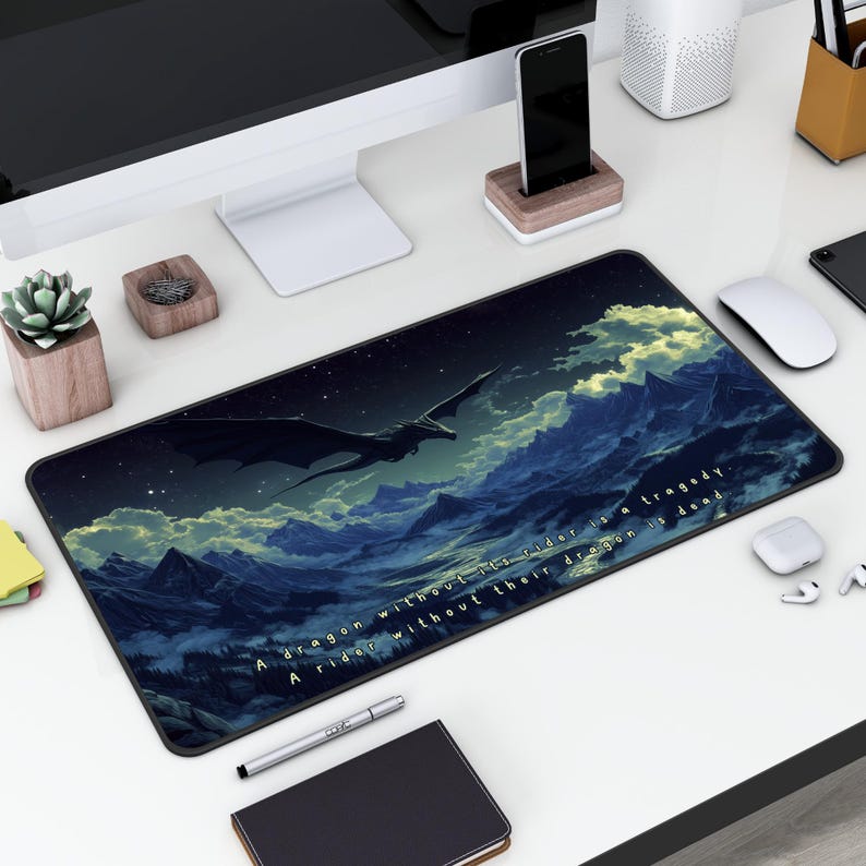 May include: A black and blue gaming mouse pad with a dragon flying over a mountain range. The text on the mouse pad reads "A dragon without its rider is a tragedy. A rider without their dragon is dead."